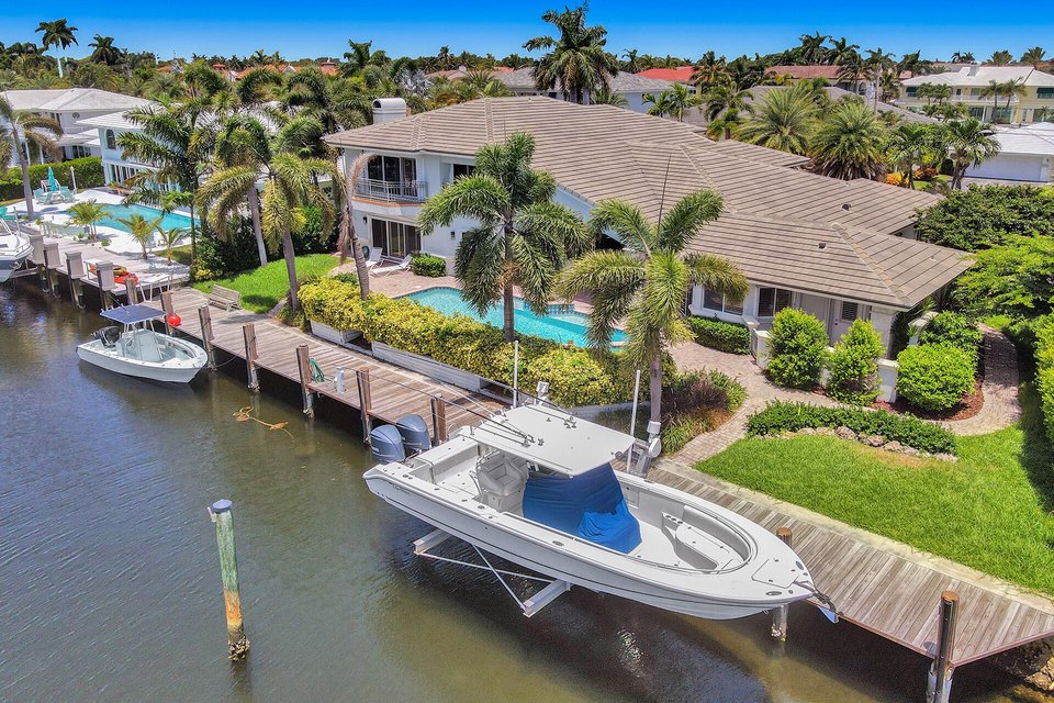 Florida waterfront home with private dock, boat lift, and a 40-foot cruiser moored in a protected canal